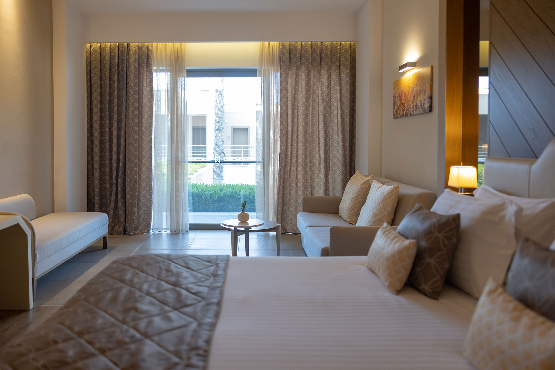 Deluxe garden view room with king bed, soft beige tones and seating area opening to a private terrace