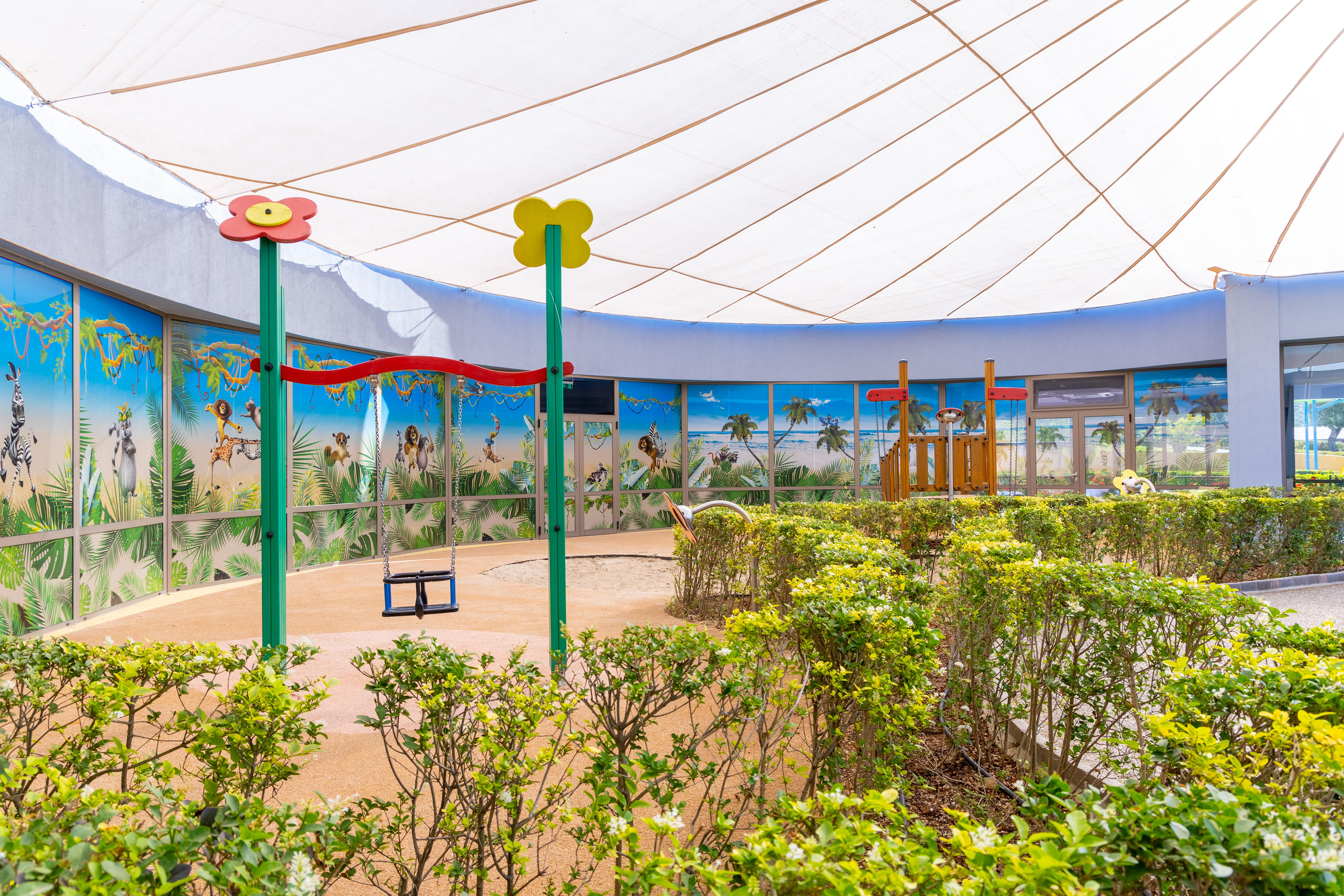 Shaded outdoor play area with swing and colorful wall murals at Kids Planet