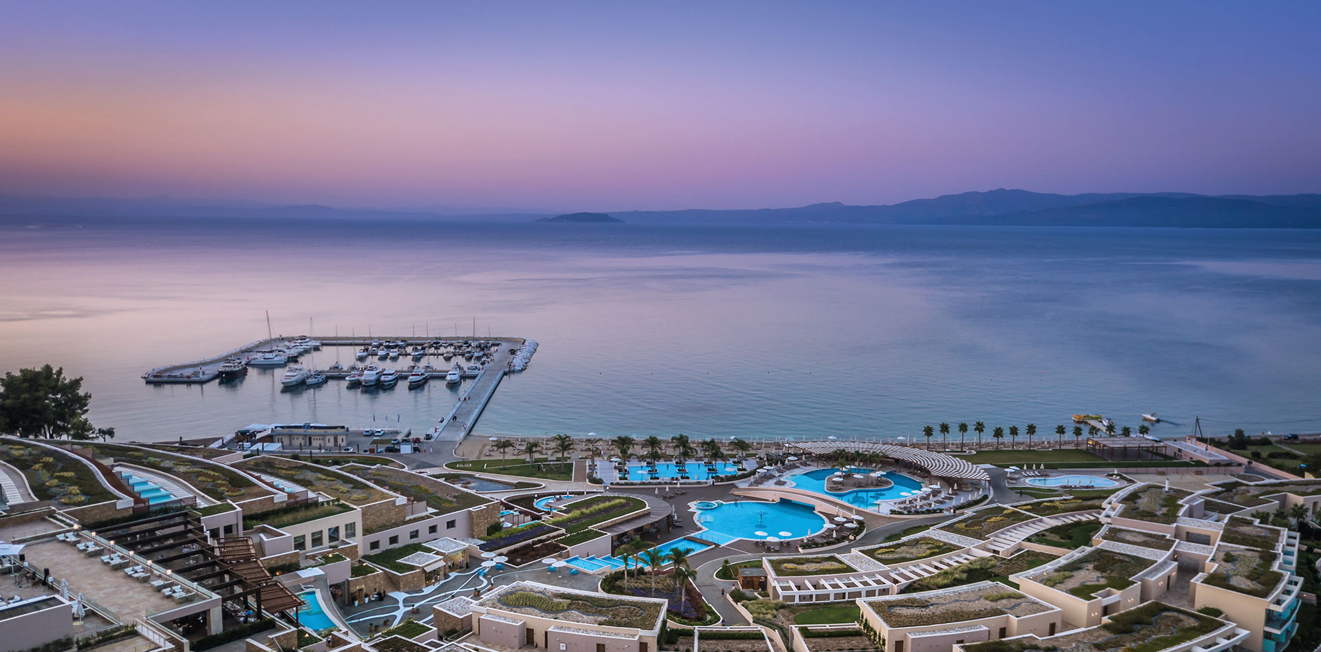 Aerial evening view of Miraggio Resort and marina under purple sunset sky