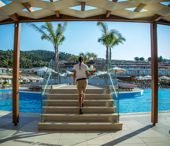 Waitress going to serve freshly made cocktails through the pool bridge of Oasis Pool Bar