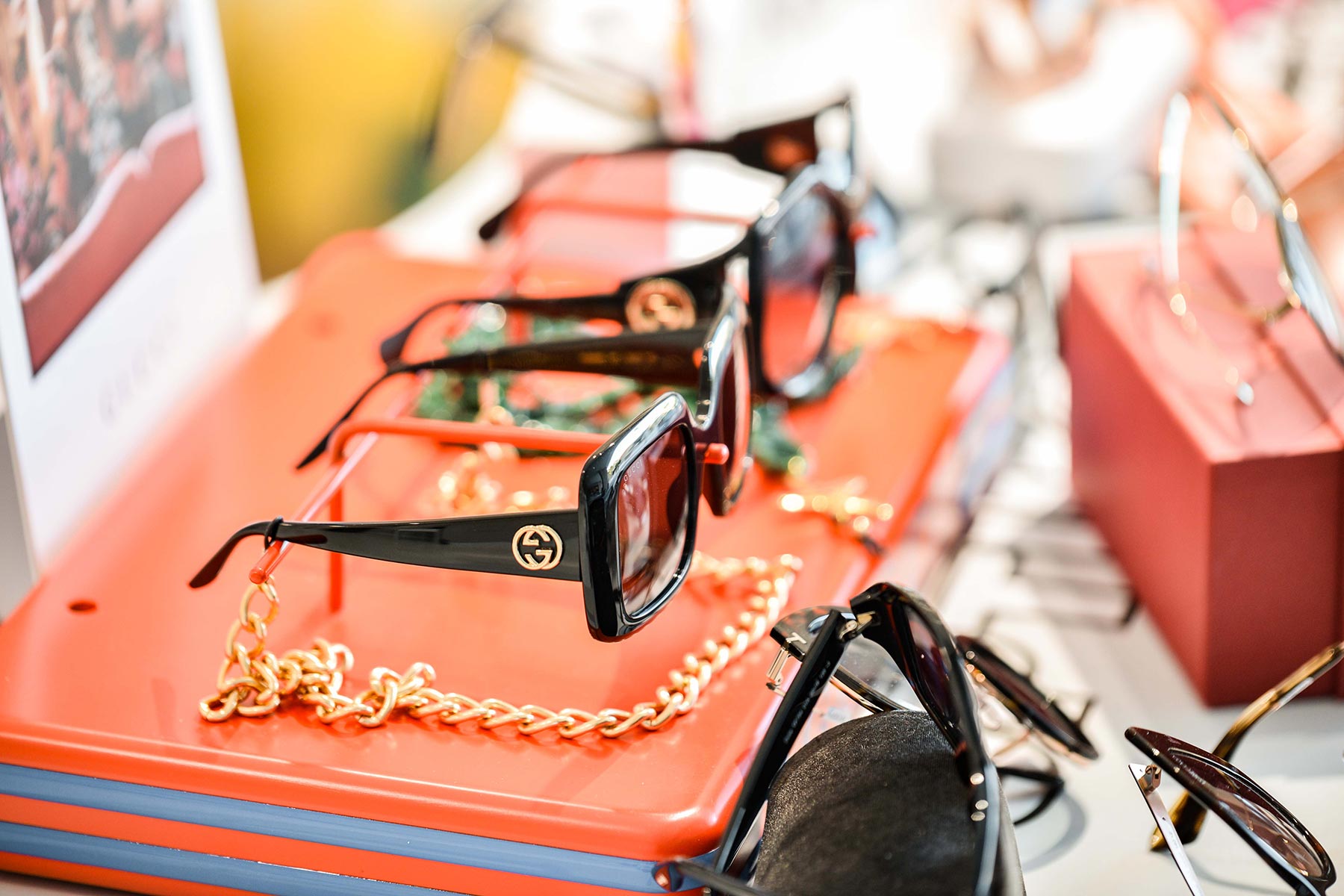 Display of luxury designer sunglasses with gold chains and red accents