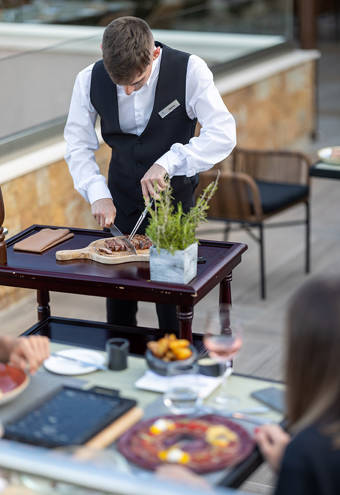 Waiter cutting up a steak before serving
