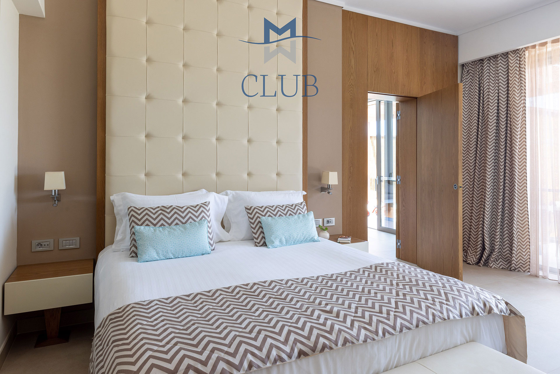 Club sea view room's king size bed with leather headboard bedside table and wooden wall details