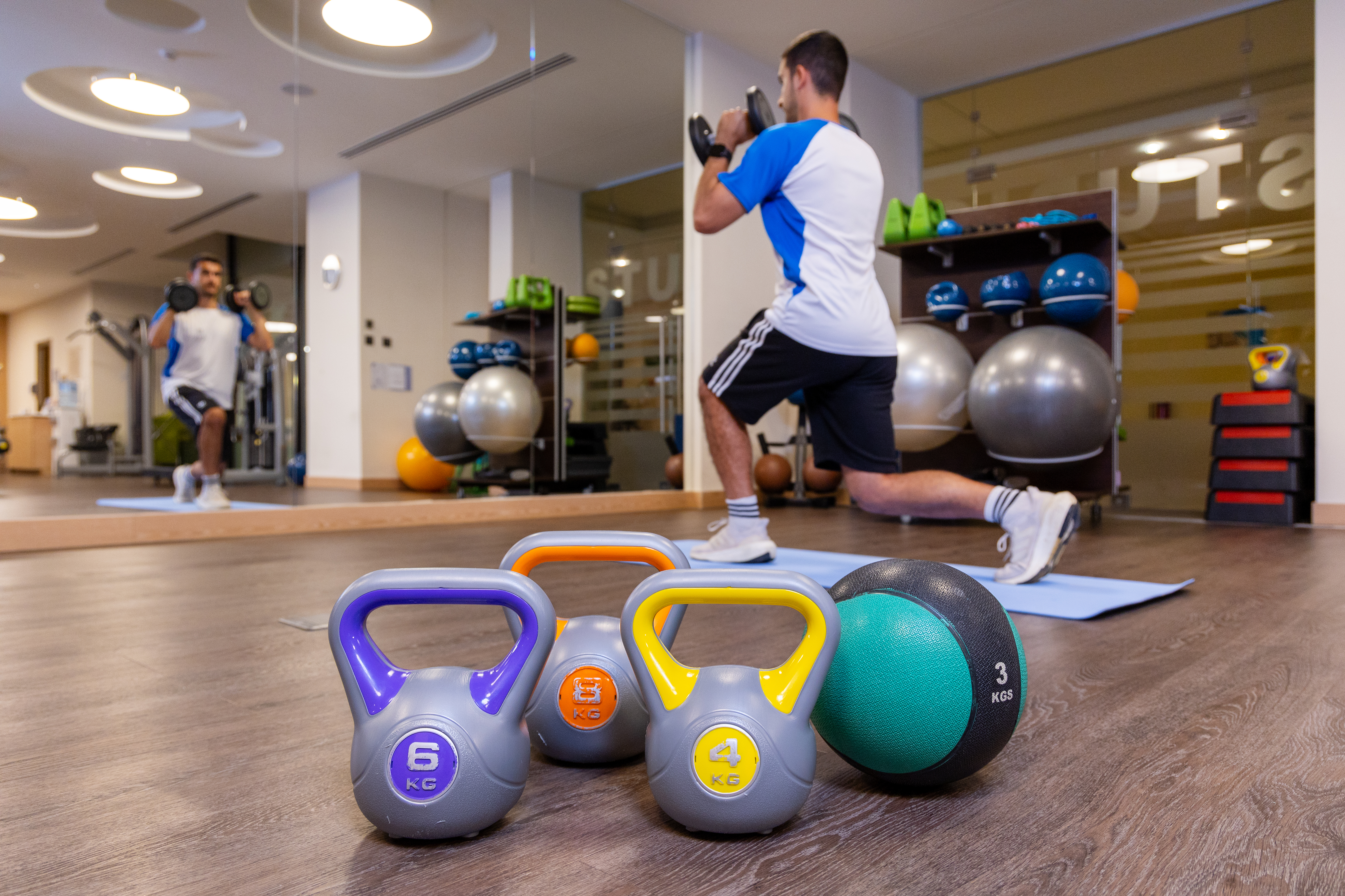 Gym equipment ang weight with a guest working out in the background