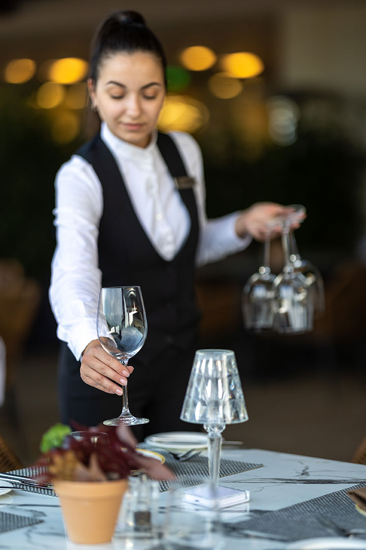 Waitress setting wine glasses on an elegant table at Sommelier's 8 restaurant