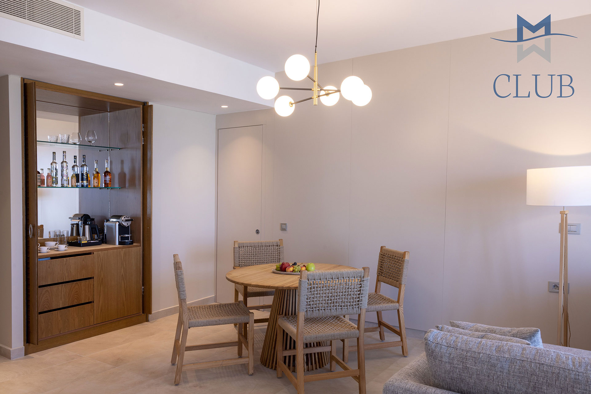 Modern suit's living area with dining table and minibar with coffee machine
