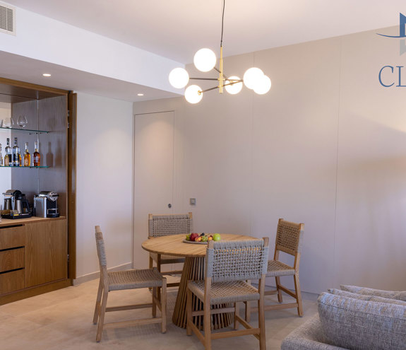 Modern suit's living area with dining table and minibar with coffee machine