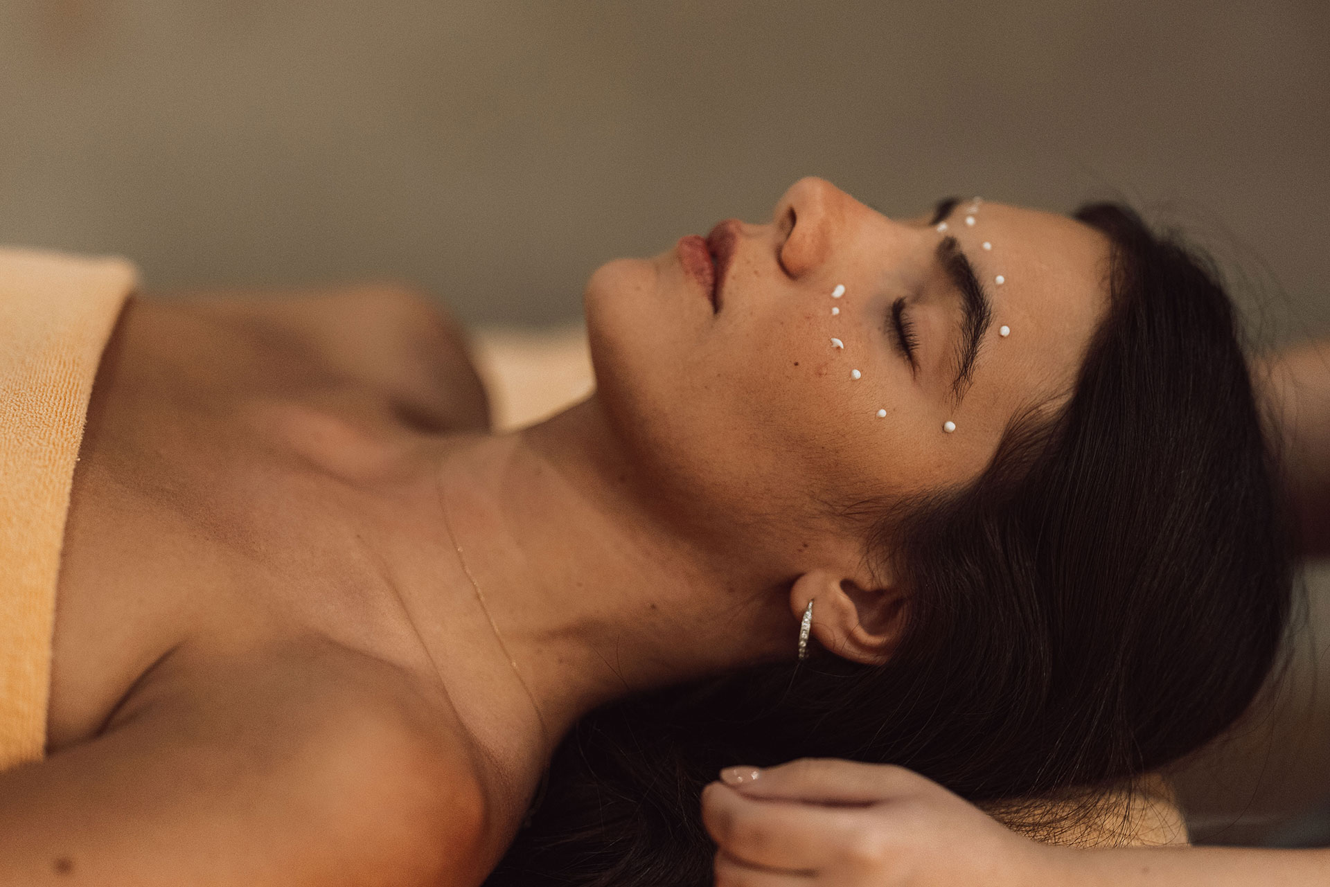 Woman relaxing during facial treatment with soothing cream applied