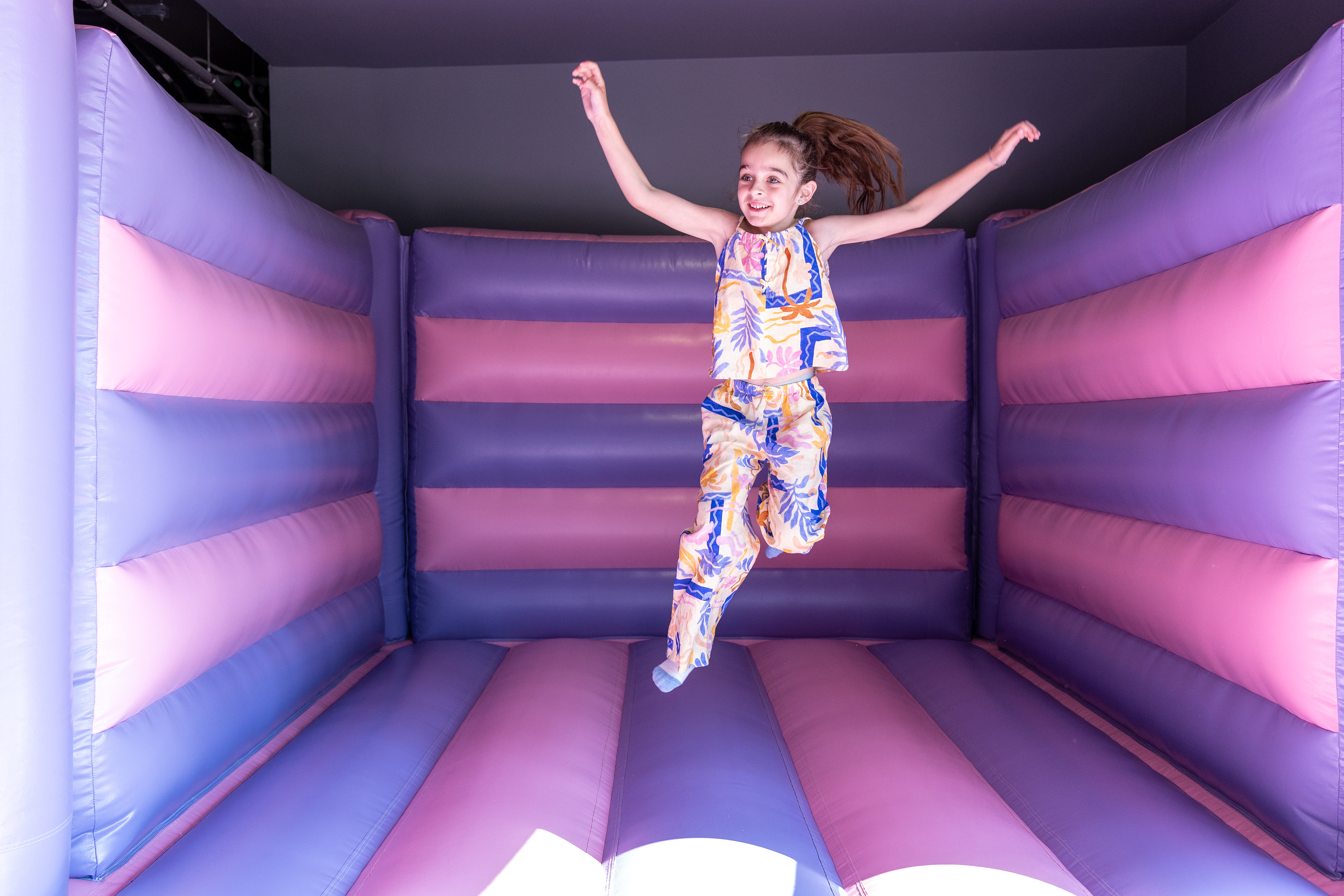 Smiling girl jumping on the colorful inflatable bouncer at Kids Planet