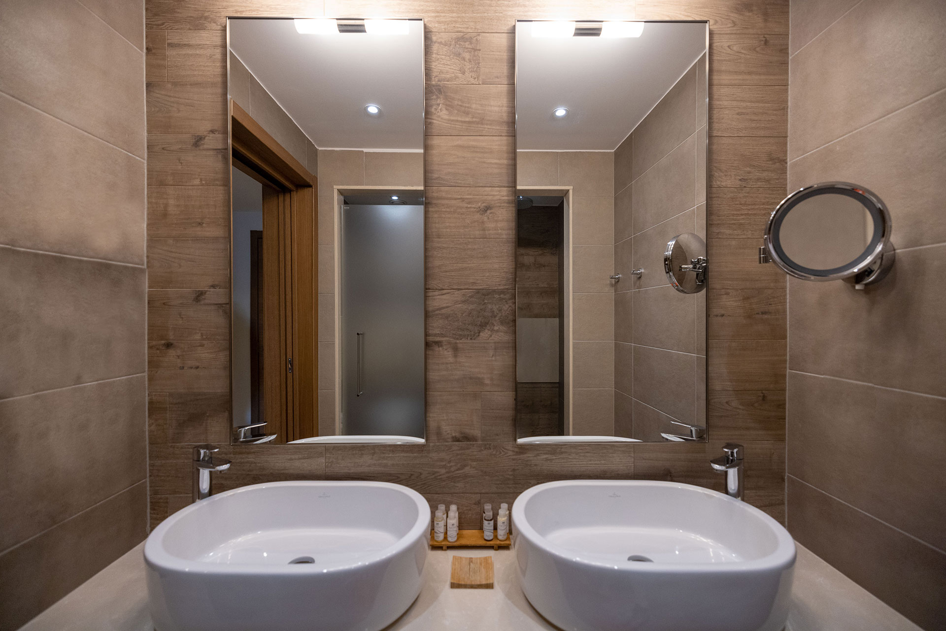 Modern bathroom with twin basins, wooden wall accents and luxury amenities