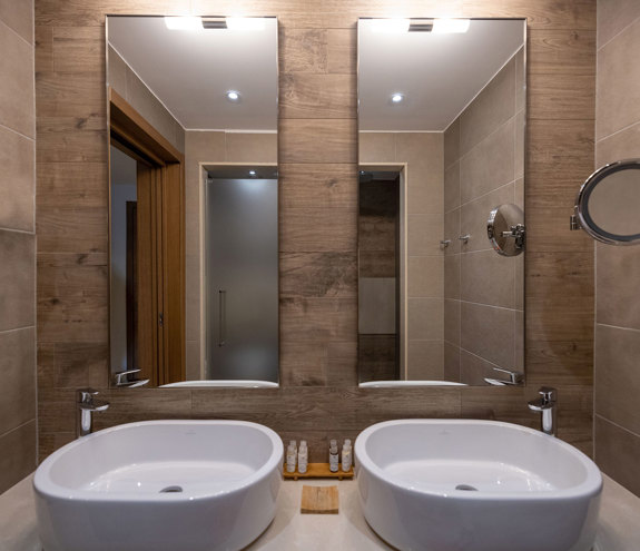 Modern bathroom with twin basins, wooden wall accents and luxury amenities