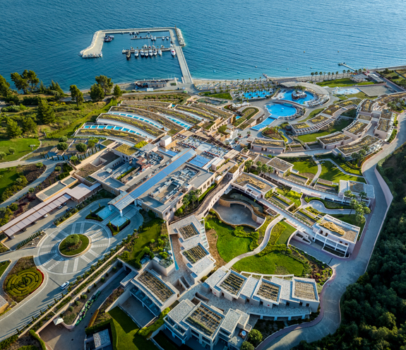 Aerial view of Miraggio Resort featuring its private marina, cascading architecture, and beachfront pools by the Aegean Sea