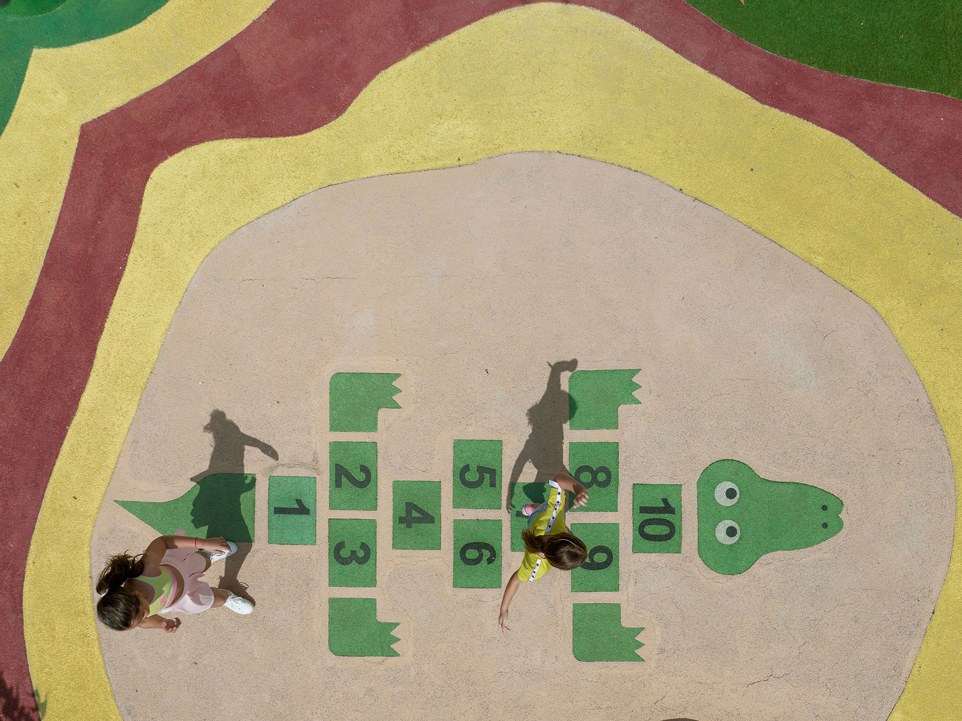 Top down view of kids playing hopscotch in the outdoor playground of Kids Planet