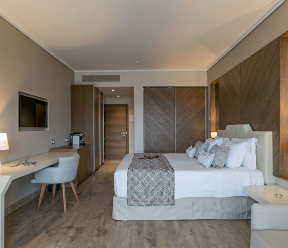 Deluxe garden view room with king bed, wooden wall design and elegant workspace with soft lighting