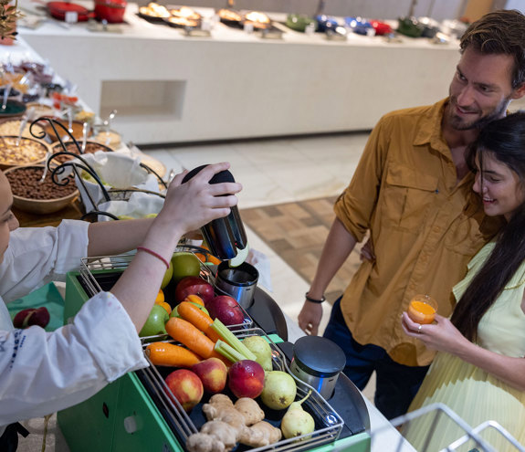 Couple watching a chef prepare fresh juice at the breakfast buffet