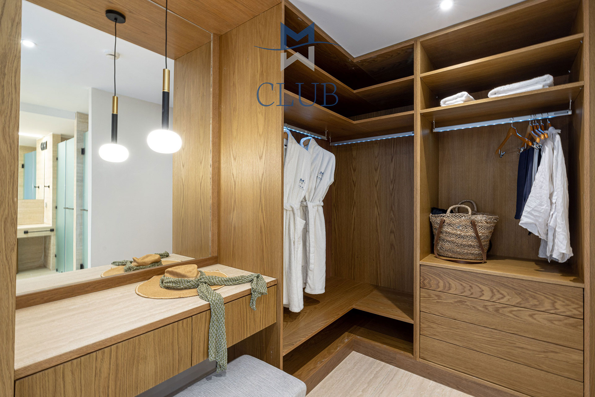 Modern wooden wardrobe in the suite, with vanity area, and soft lighting