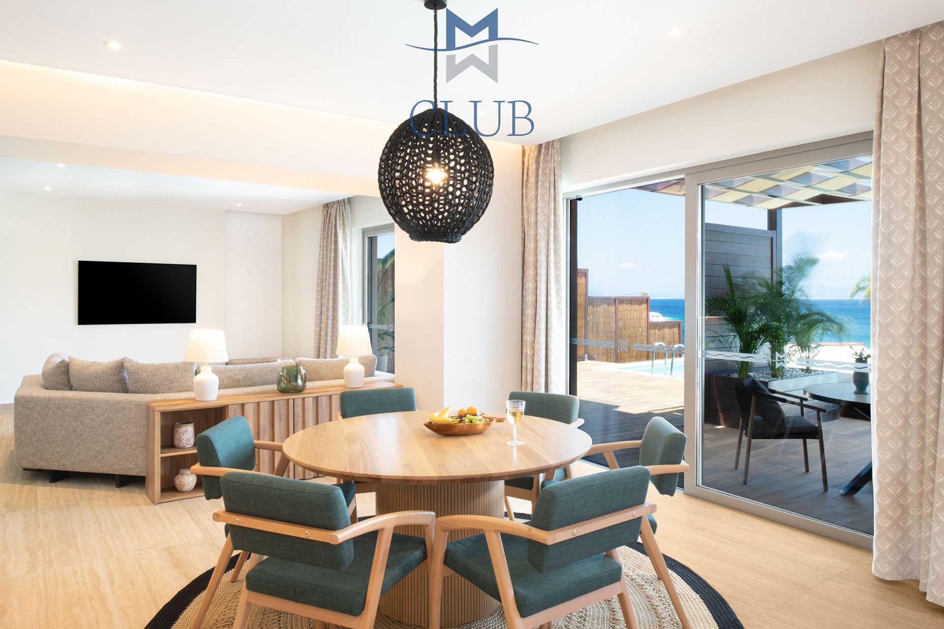 Spacious living room with dining table, seating area with wall mounted TV and balcony doors accessing private terrace