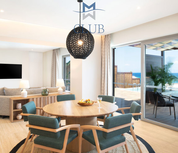 Spacious living room with dining table, seating area with wall mounted TV and balcony doors accessing private terrace