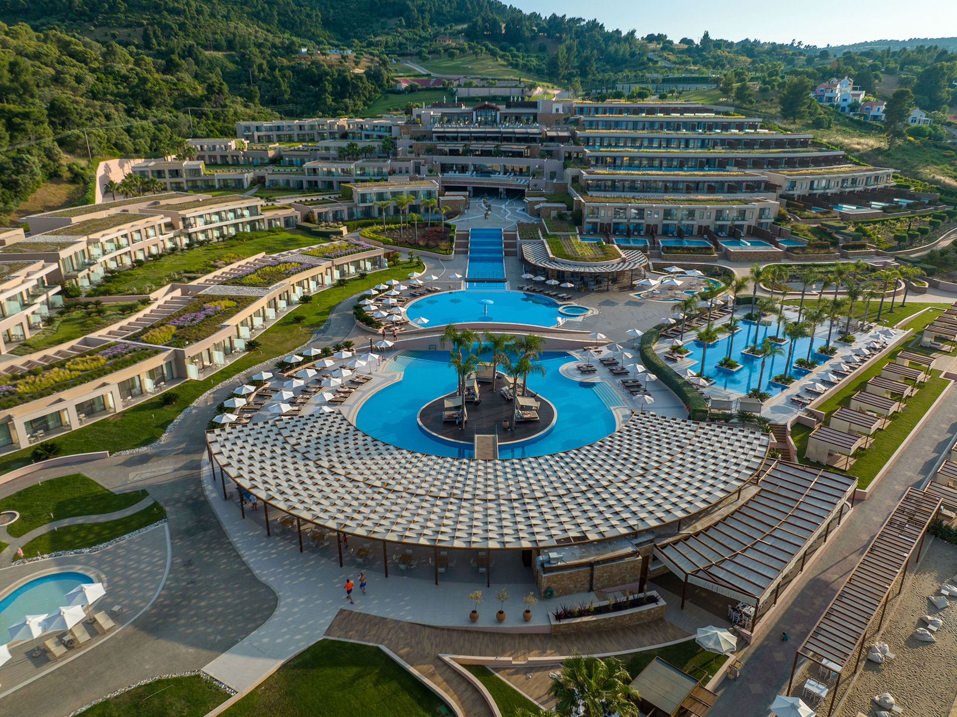 Aerial view of the resort's main pools, cascading architecture, and lush hillside surrounding