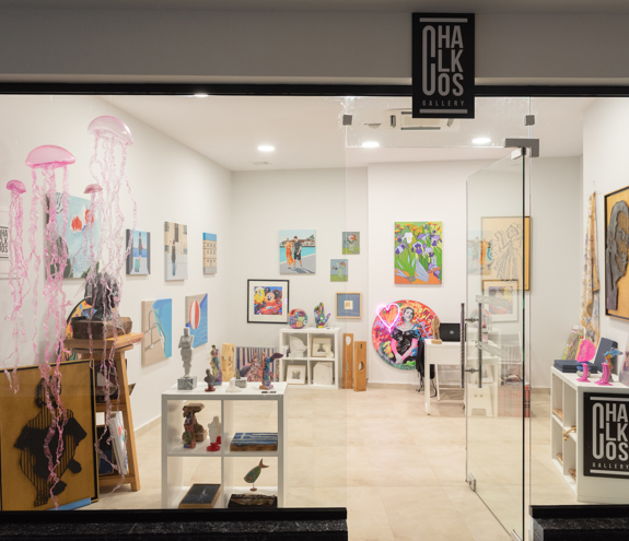 Chalkos Art Gallery storefront displaying sculptures, framed artworks, and pink jellyfish decorations hanging