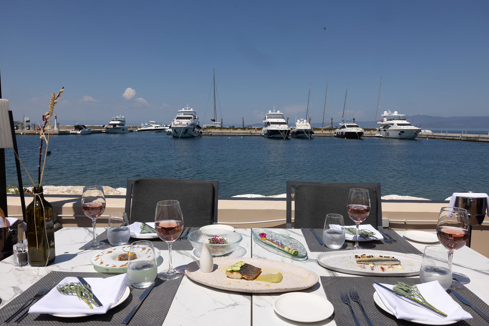 Gourmet lunch setup with rose wine and marina view at Toroneo restaurant