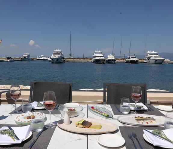 Toroneo Restaurant table with food and glasses of wine and background of the marina