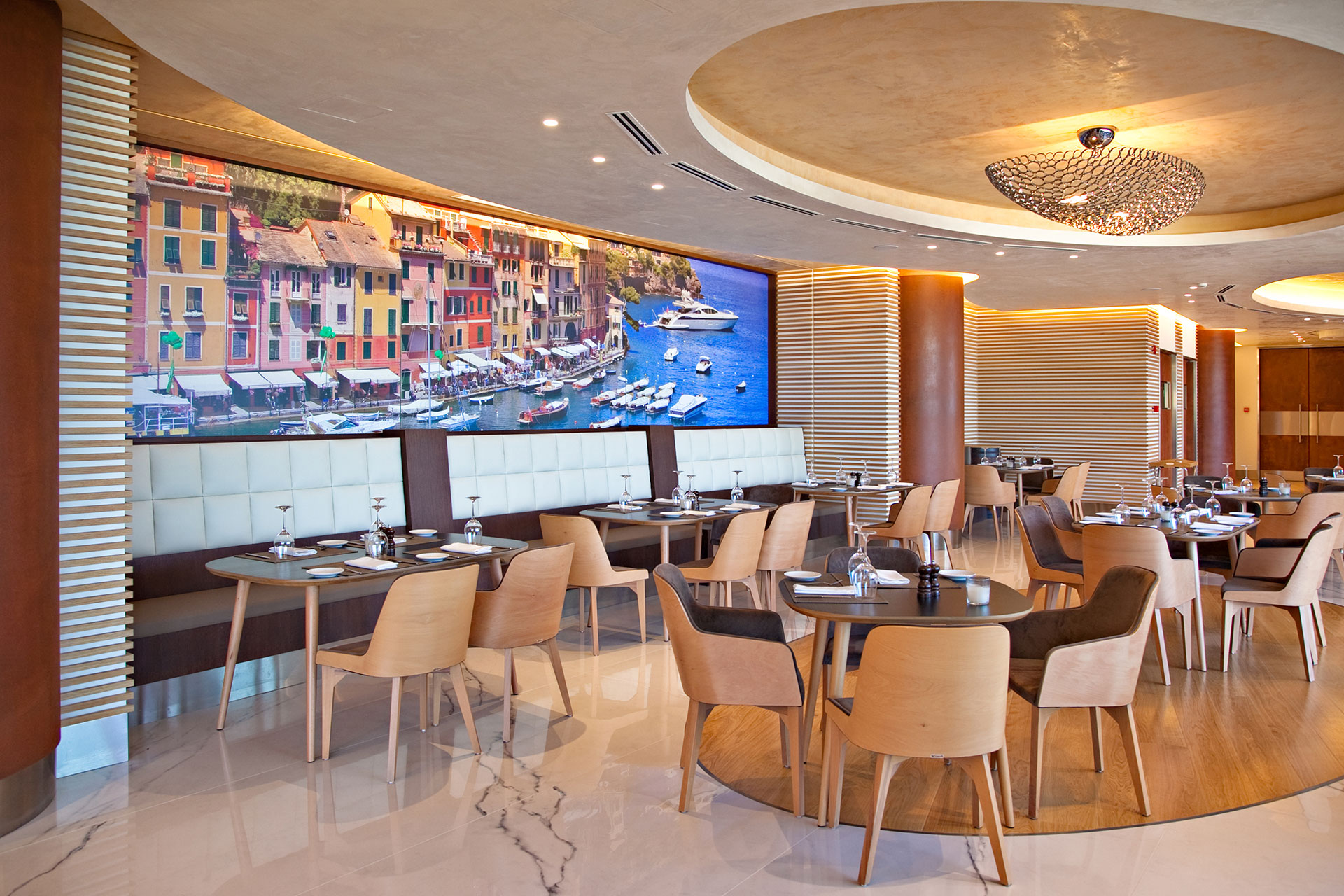Portofino restaurant interior with wall art of colorful Portofino harbor and elegant dining tables