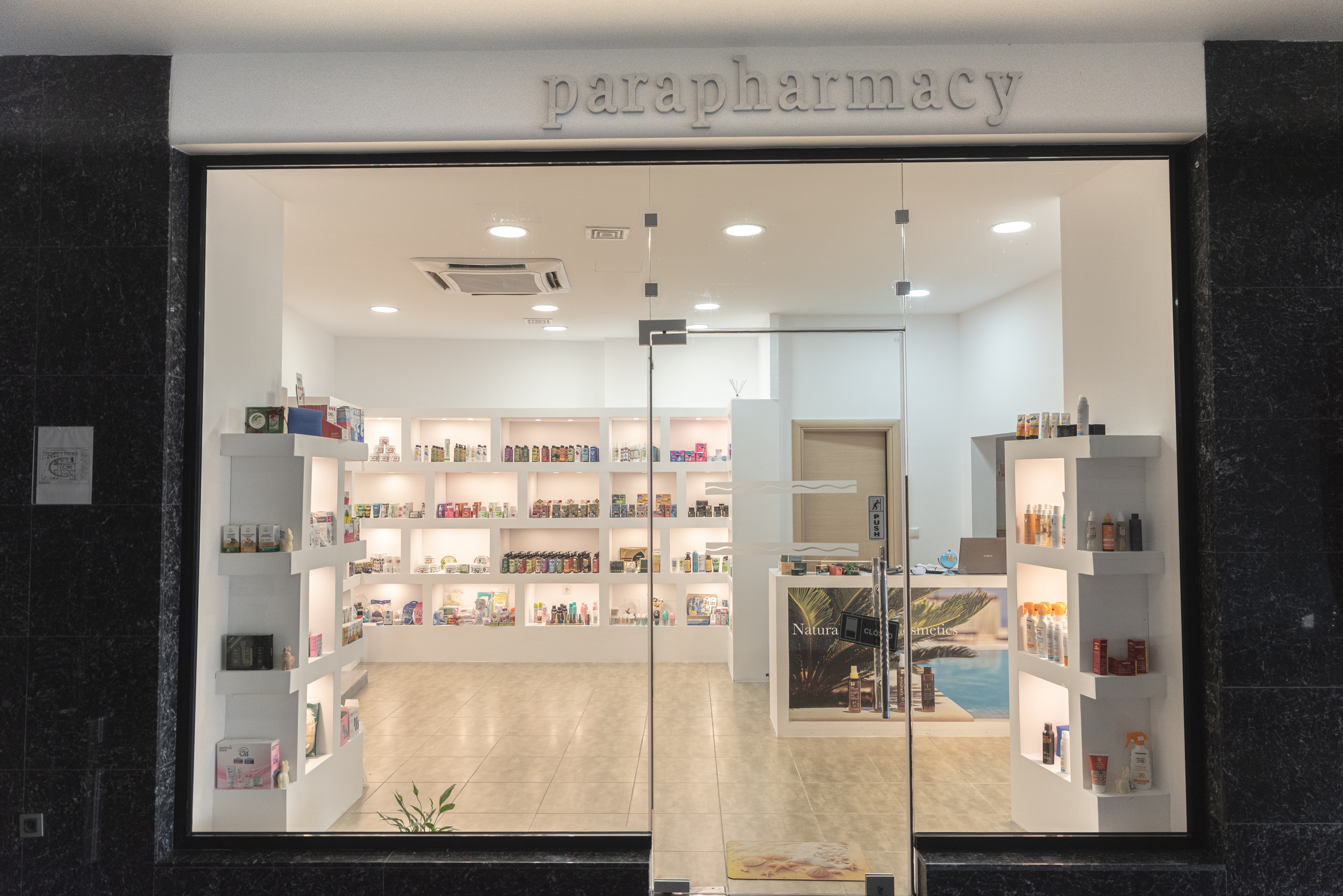 Pharmacy storefront with beauty products, skincare, and sunscreens displayed in the window