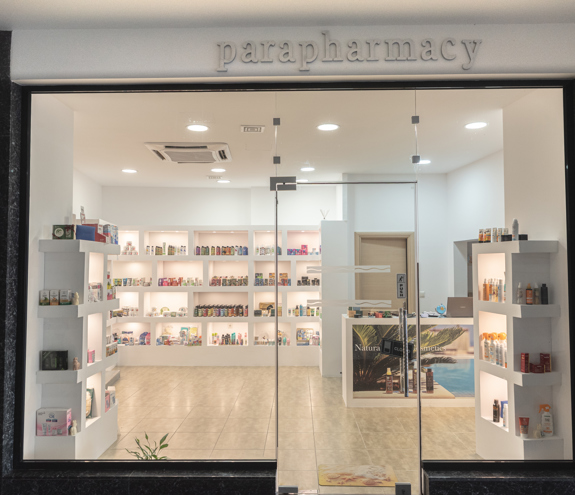 Pharmacy storefront with beauty products, skincare, and sunscreens displayed in the window