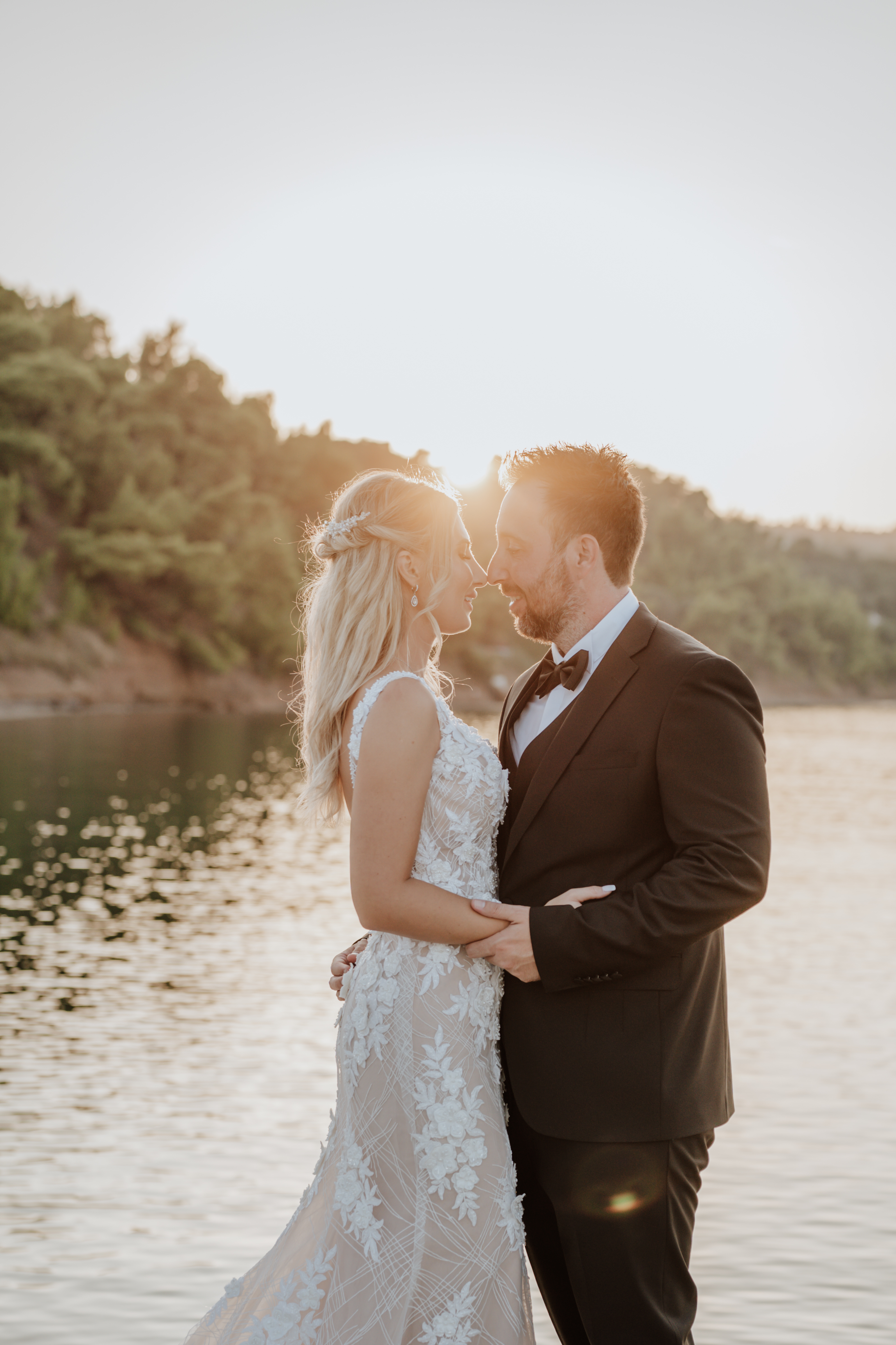Bride and groom embracing by the sea during sunset