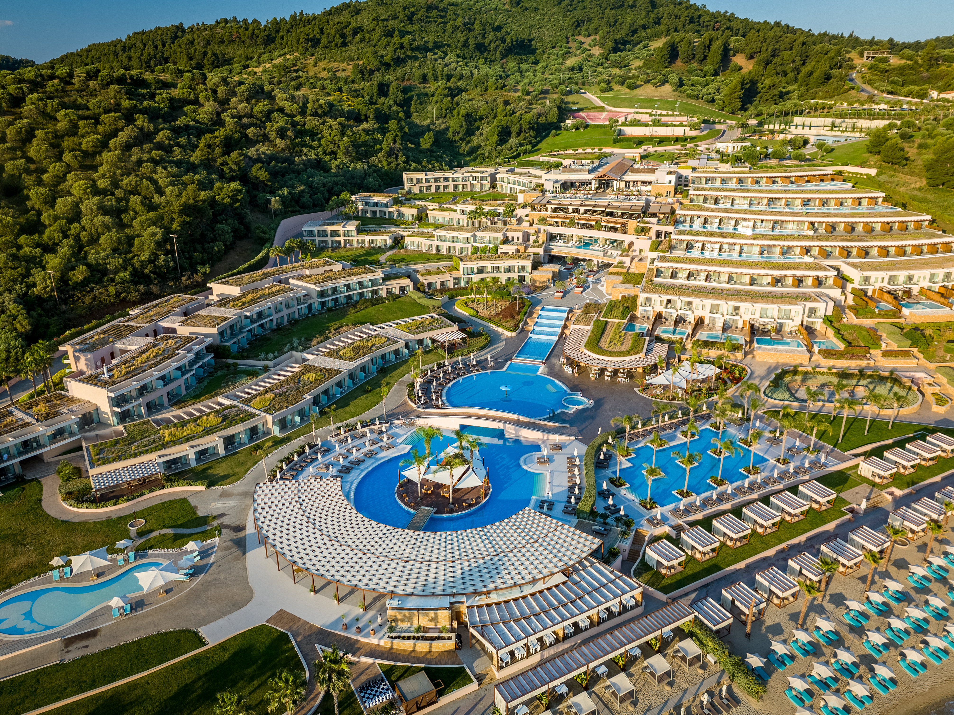 Aerial view of Miraggio Thermal Spa Resort showcasing terraced architecture, pools, cabanas, surrounded by lush hills