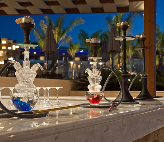Hookahs prepared on the counter of Oasis Beach Bar at night with warm ambient lighting