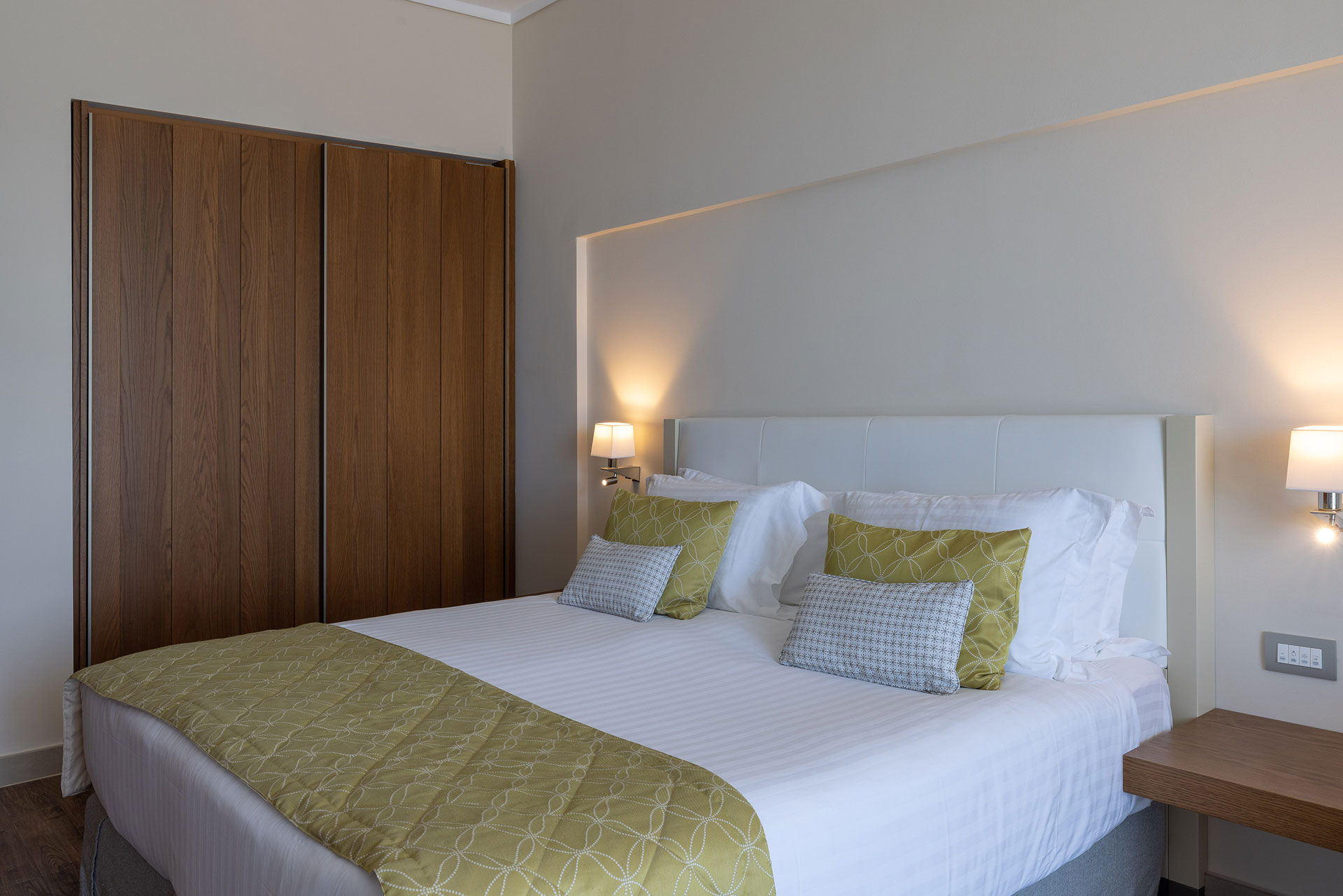 Elegant deluxe sea view room with double bed, wooden wardrobe, and ambient lighting