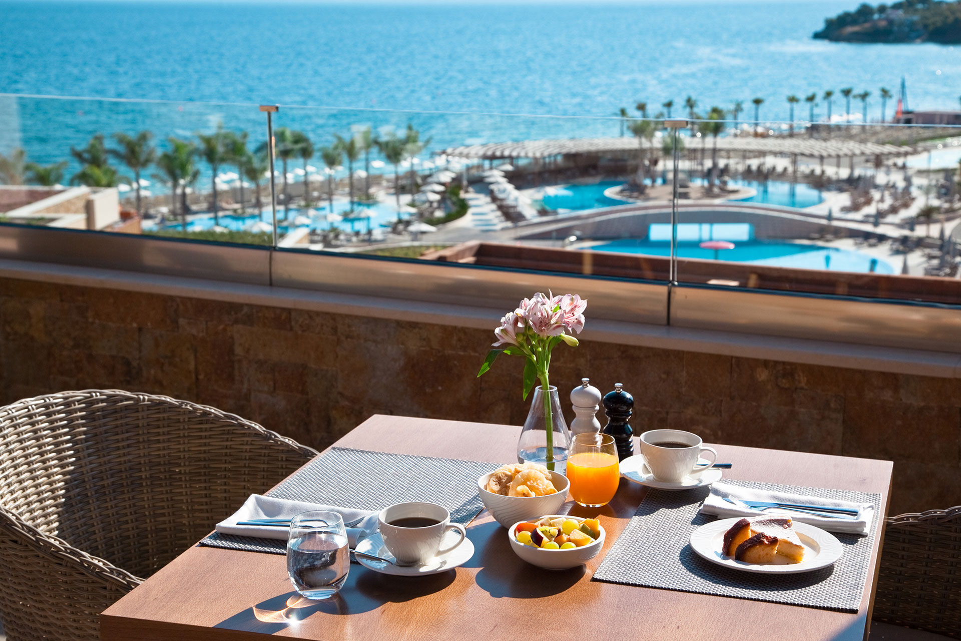 Outdoor table of Kritamo restaurant served with coffee, fresh juice and fruits, with sea view