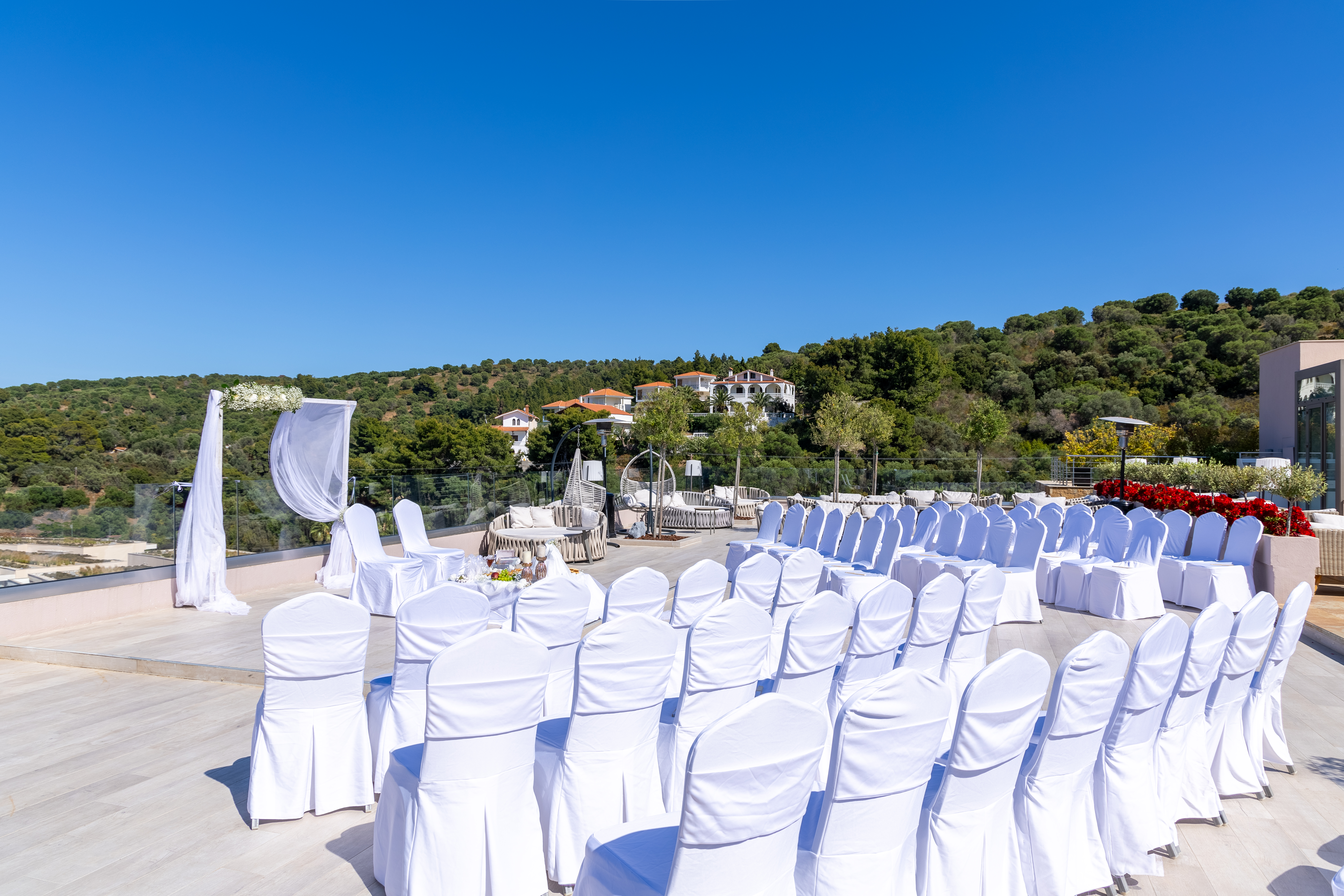 Outdoor wedding seating area with white covered chairs and scenic hillside backdrop