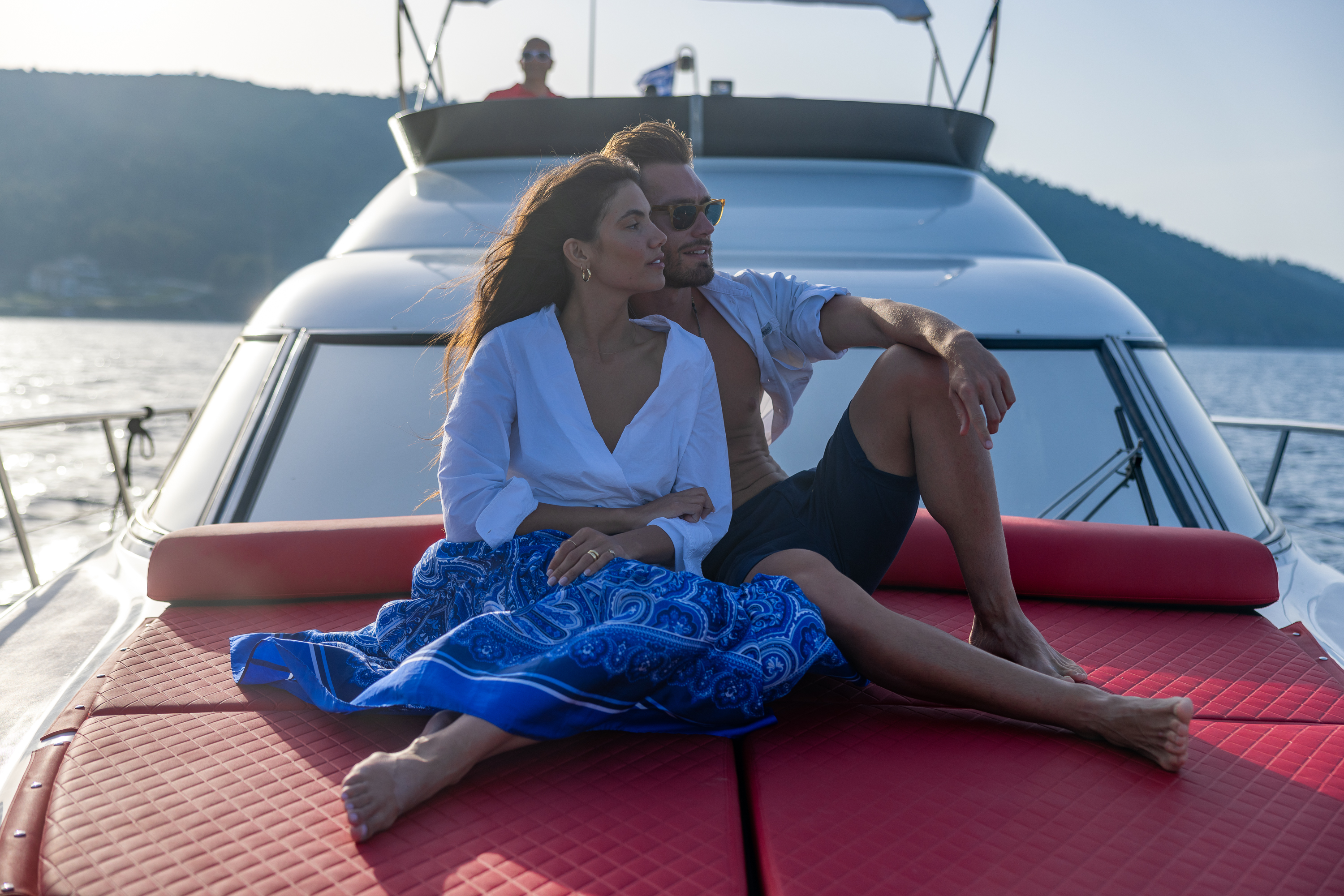 Couple relaxing on the red sunbed of a luxury yacht during a serene summer cruise
