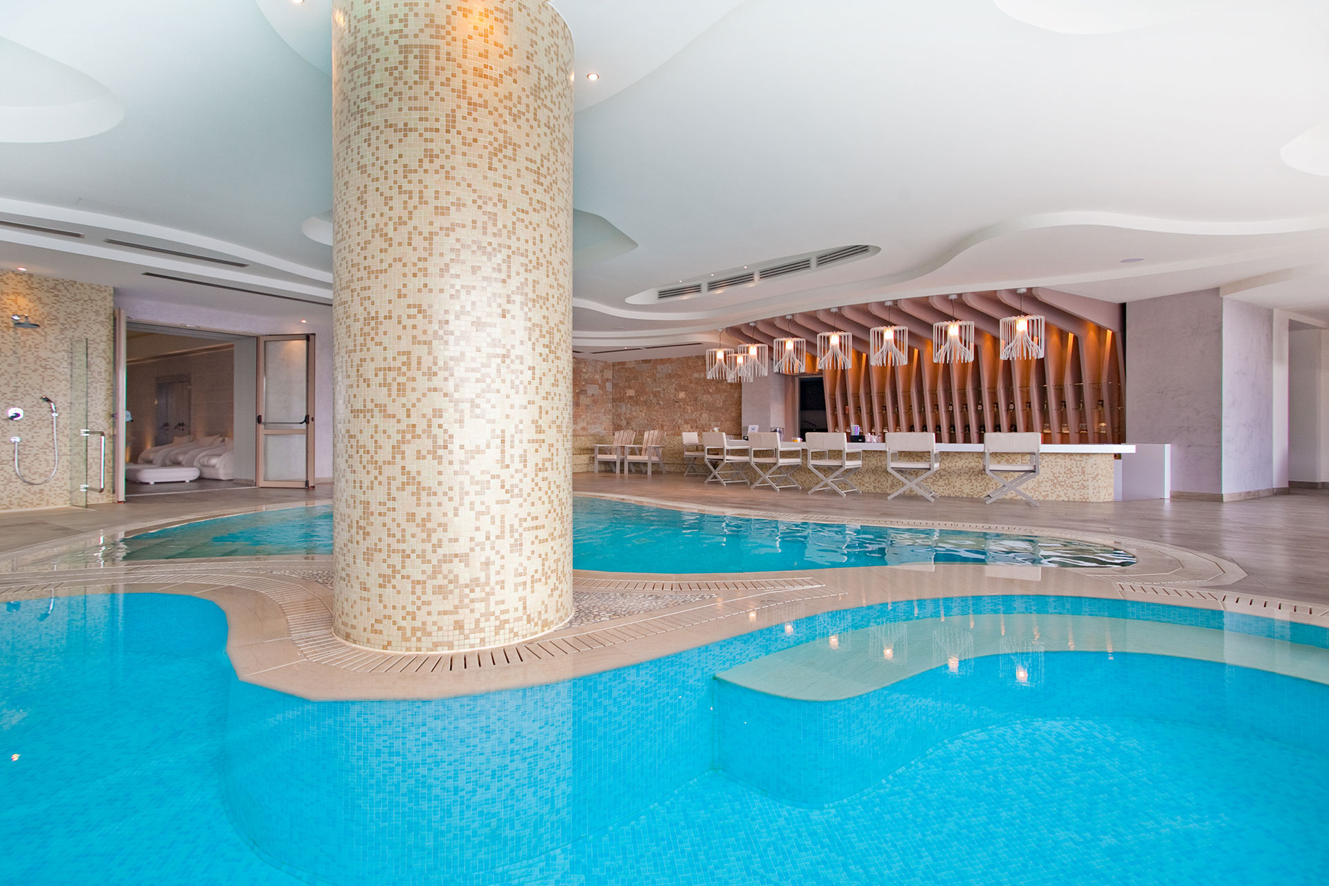 Elegant Myrthia Health Bar with seating in front of indoor infinity pools and central column