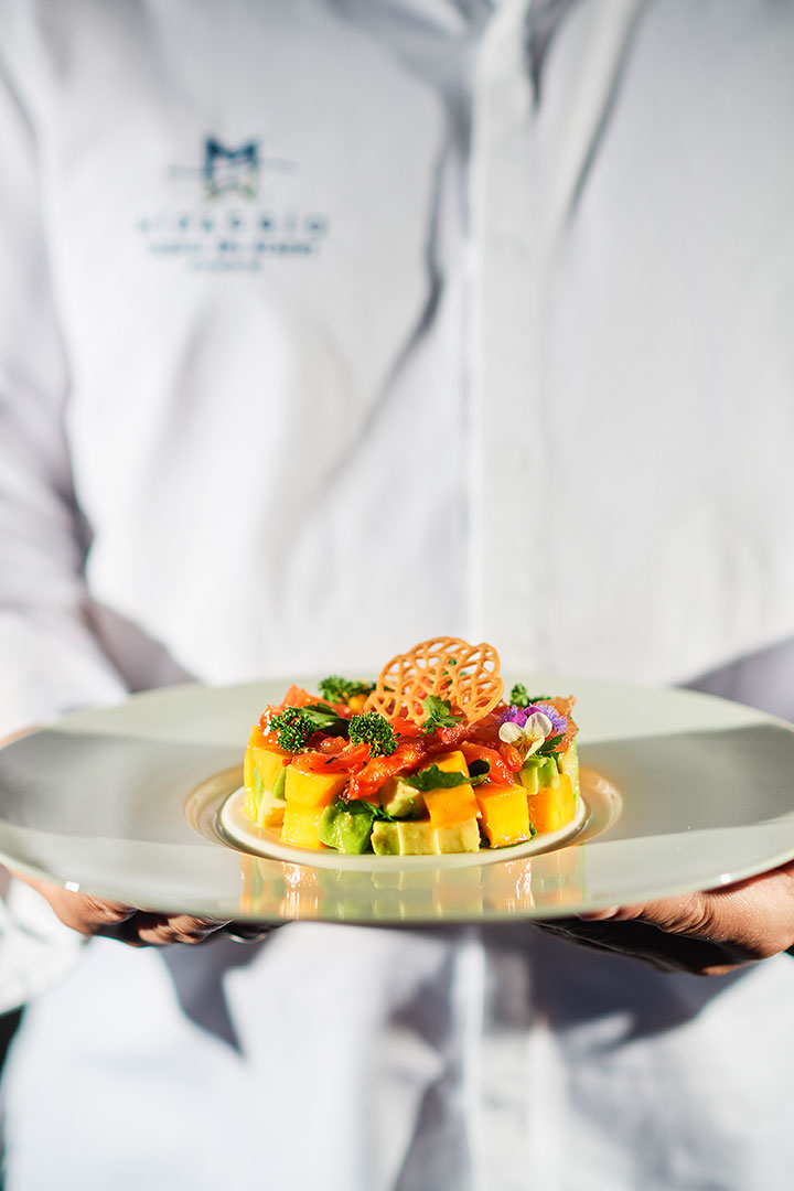 Colorful salmon tartare with mango, avocado, and herbs served on elegant plate