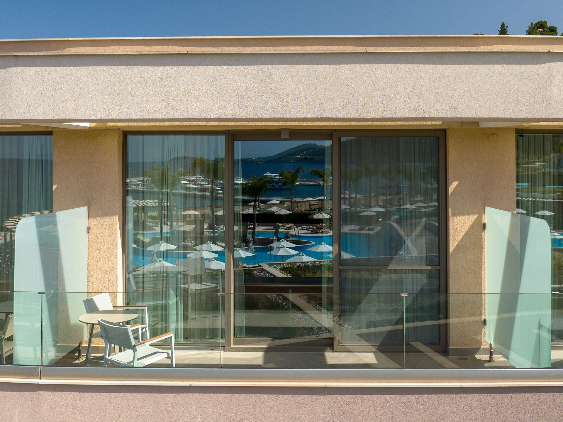Balcony of deluxe room with glass railing and marina reflection in the windows
