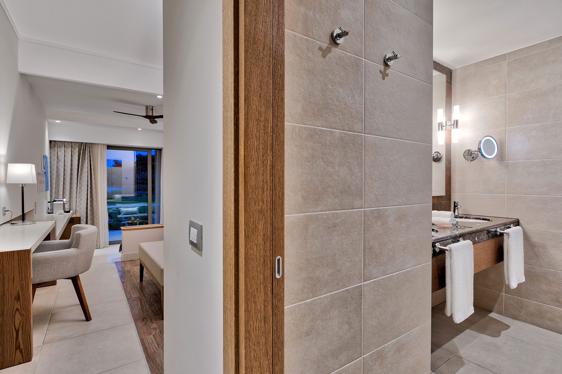 Modern family room featuring elegant beige bathroom with marble sink and spacious bedroom with garden access