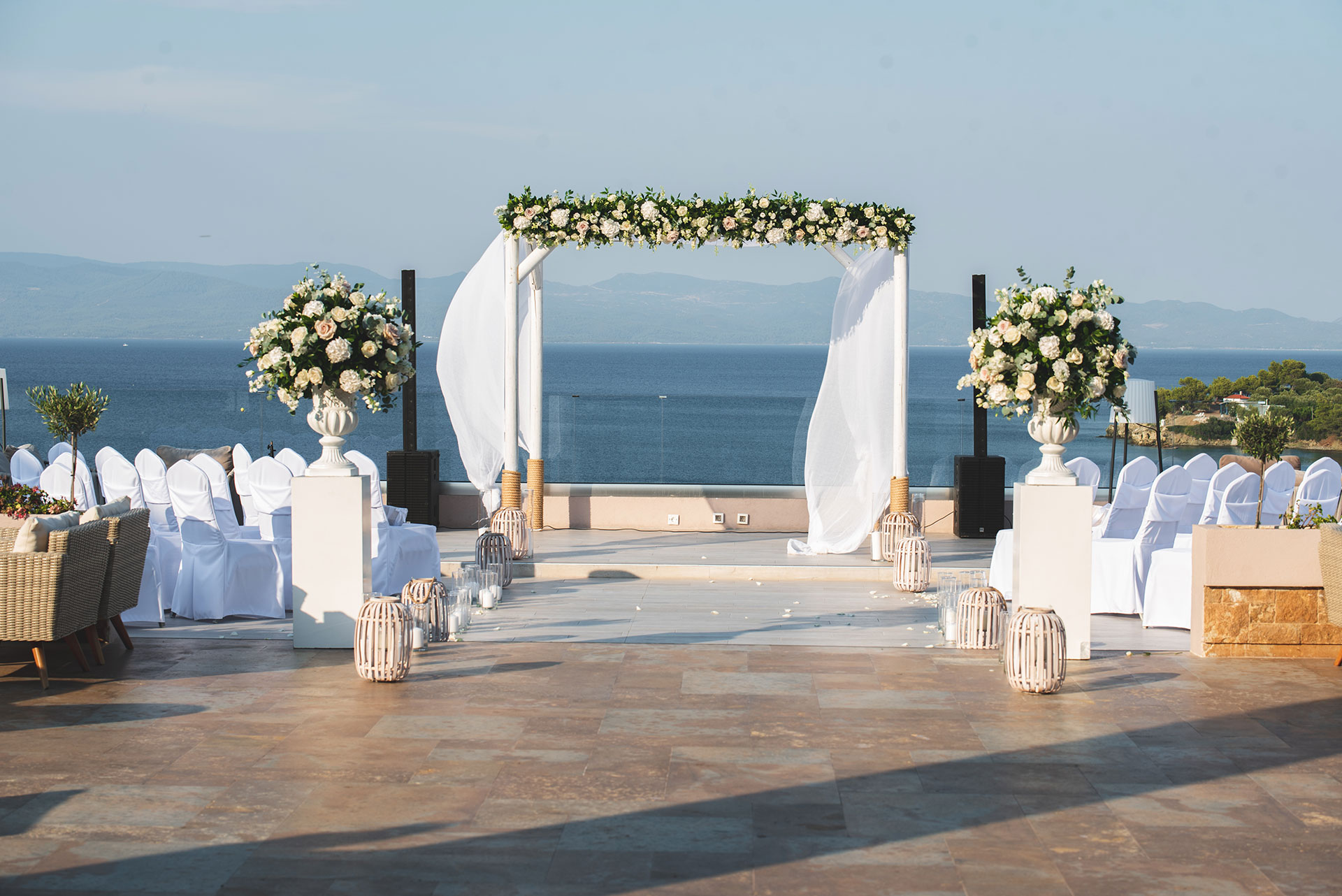 Elegant outdoor wedding ceremony setup with floral arch and sea view