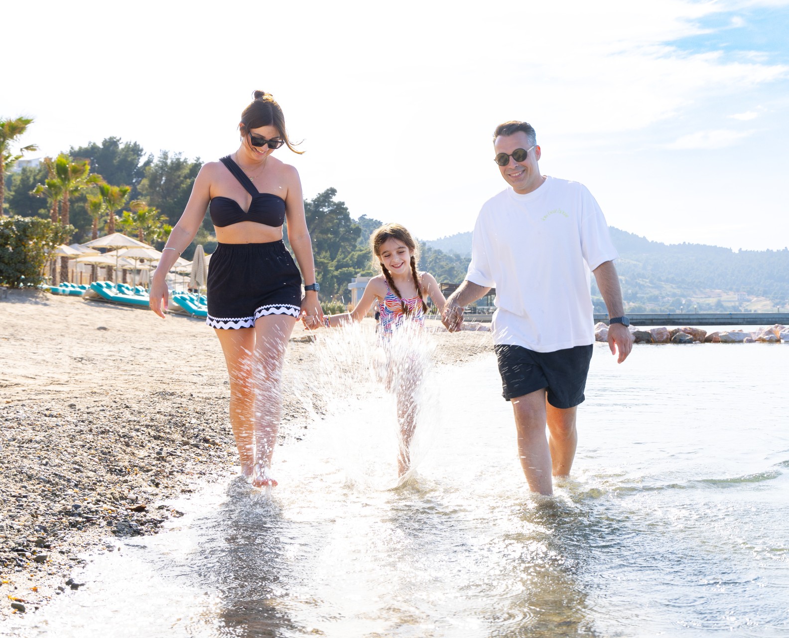 Family enjoying a sunny walk and splashing in the shallow sea