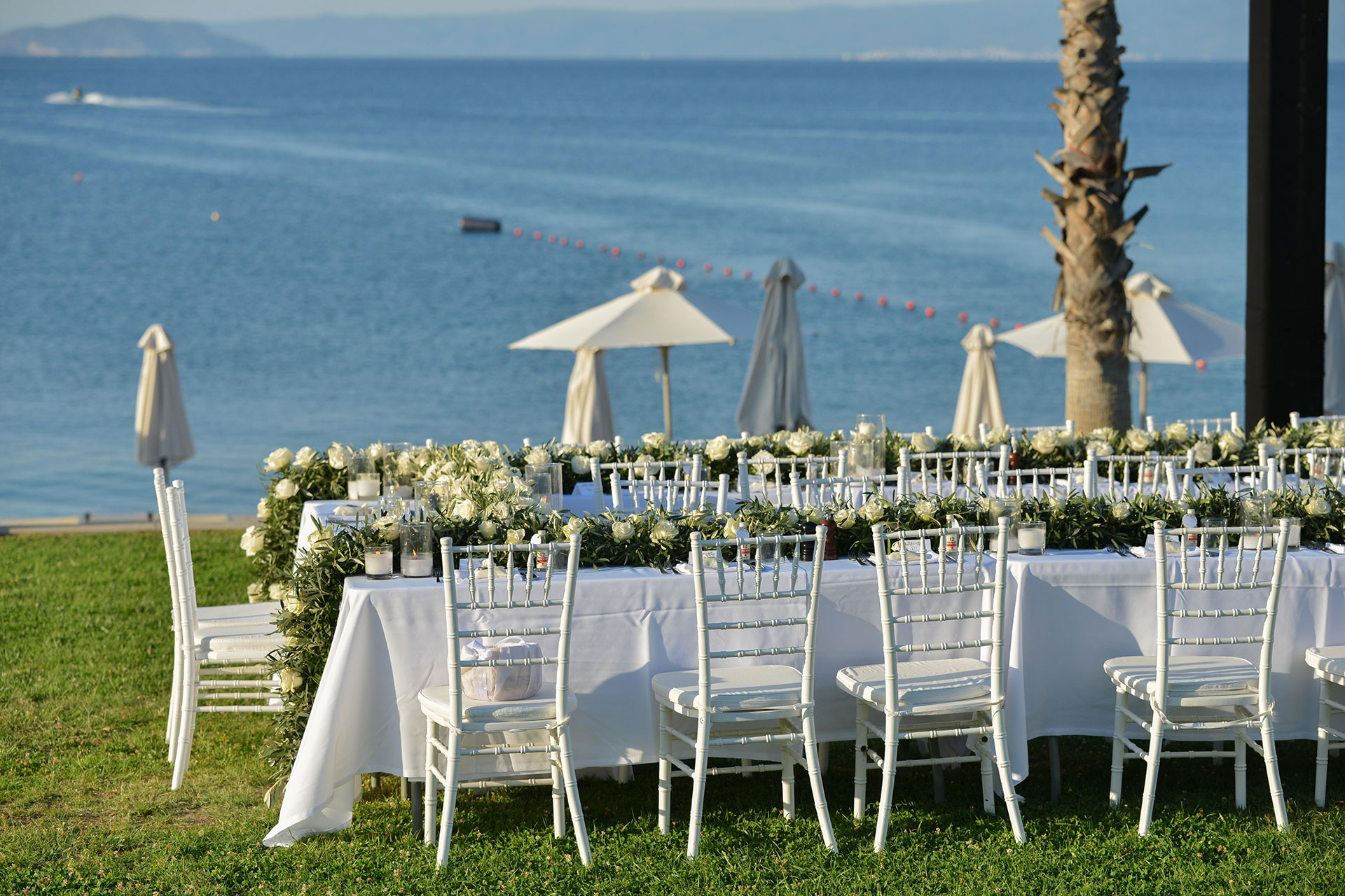 Seaside wedding dinner table with white chairs and floral centerpieces