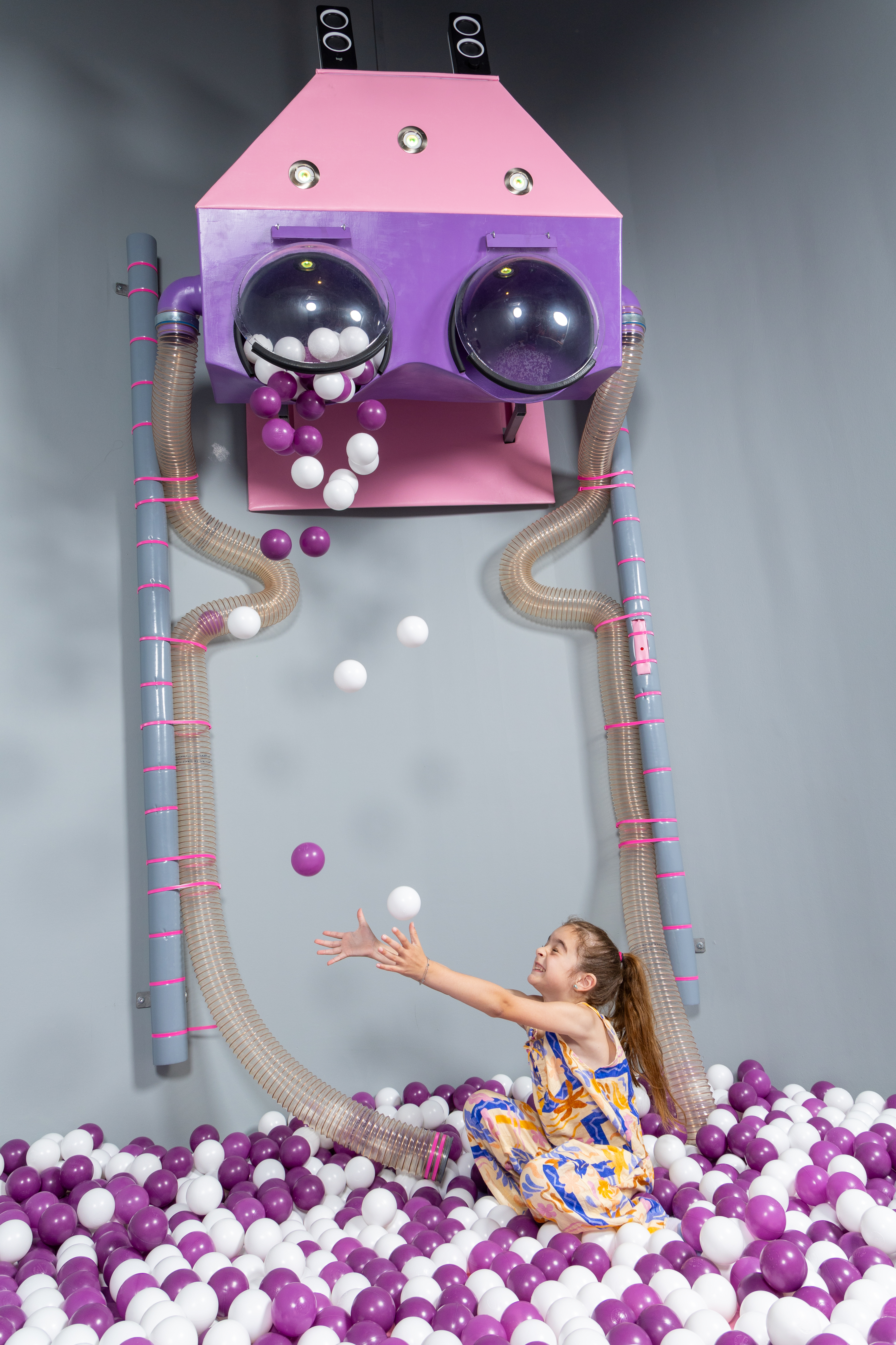 Girl playing joyfully in the purple and white ball pit at Kids Planet