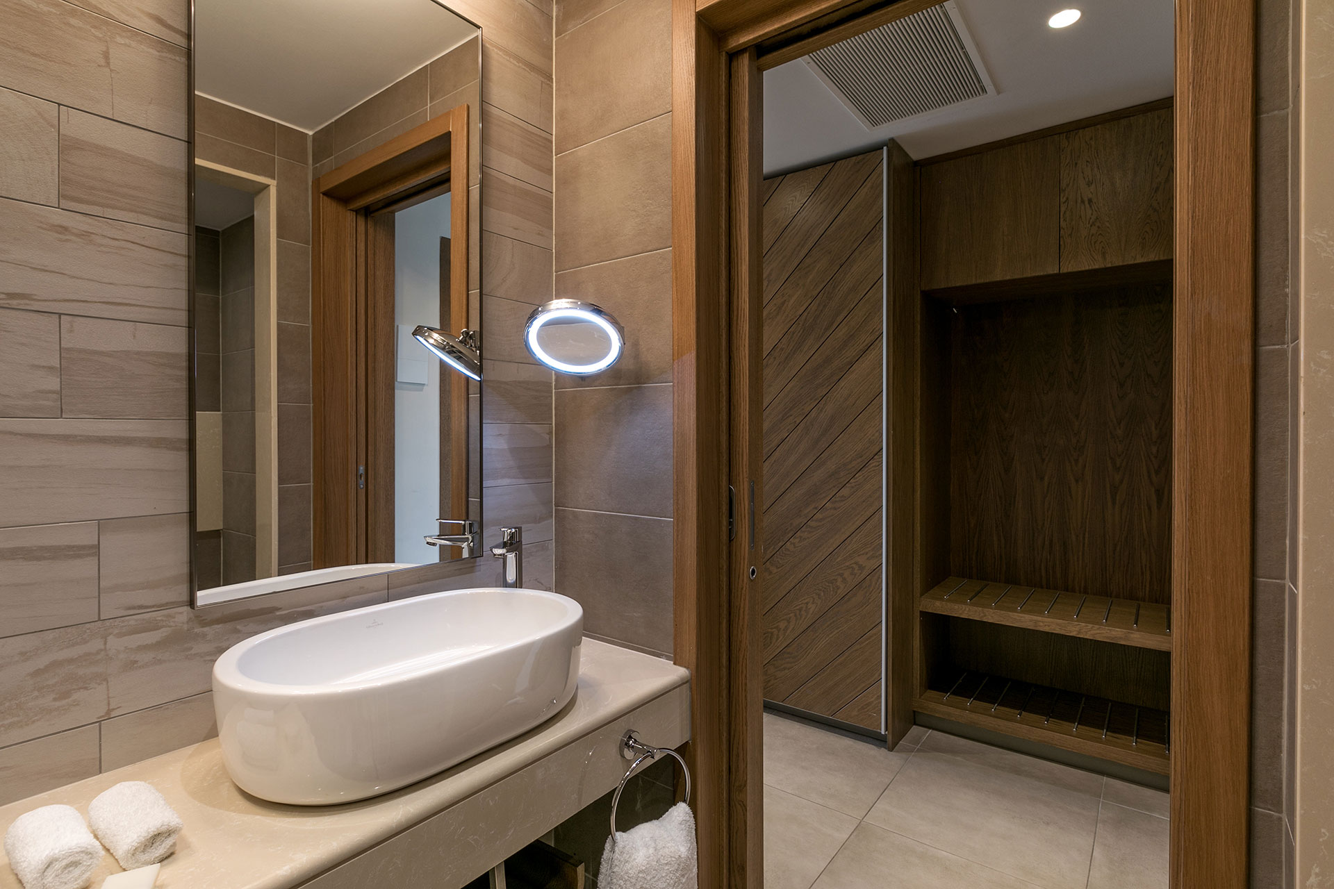 Family room bathroom with elegant sink, vanity mirror, and wooden wardrobe area