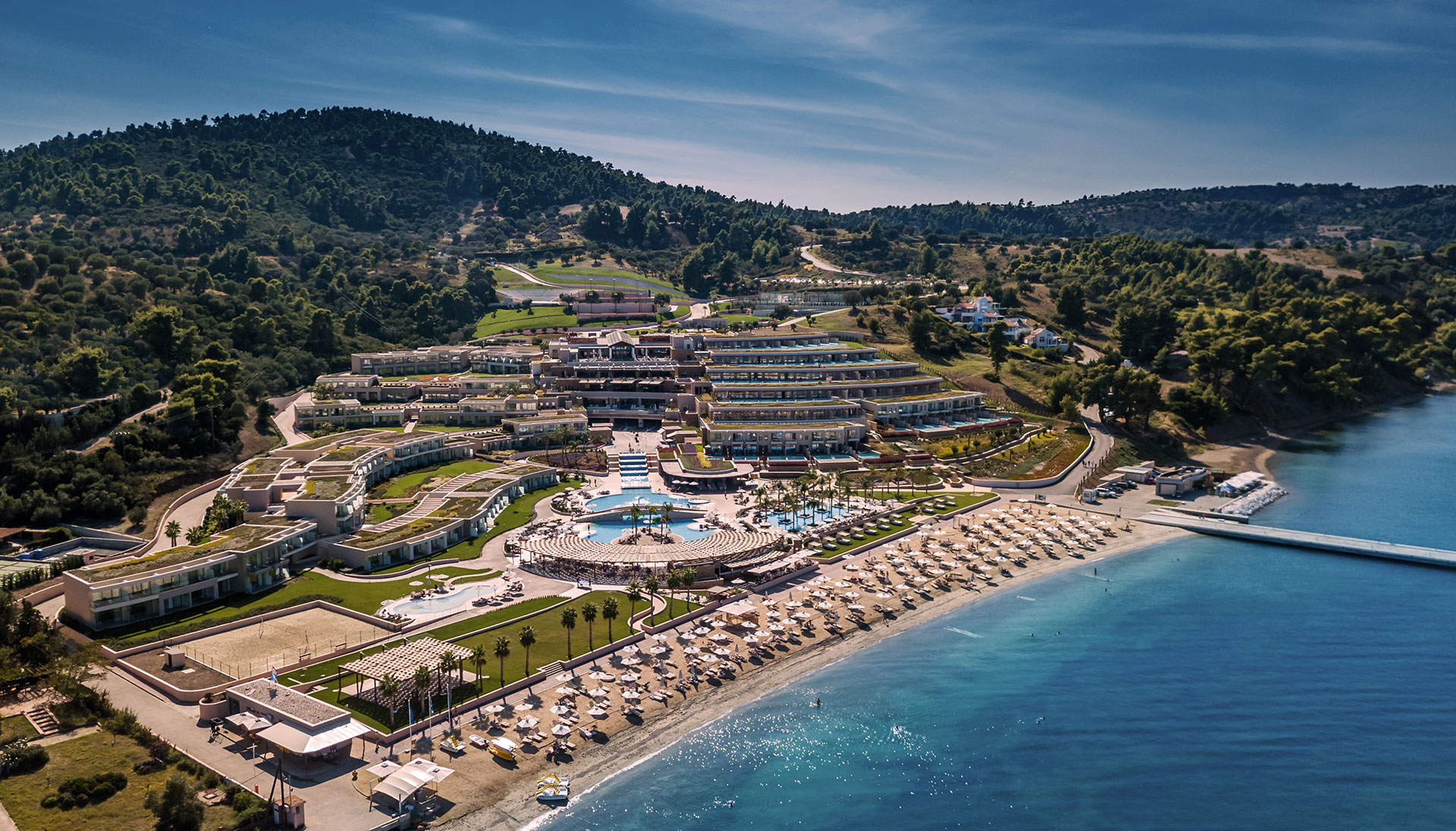 Aerial panoramic view of beachfront resort complex surrounded by hills