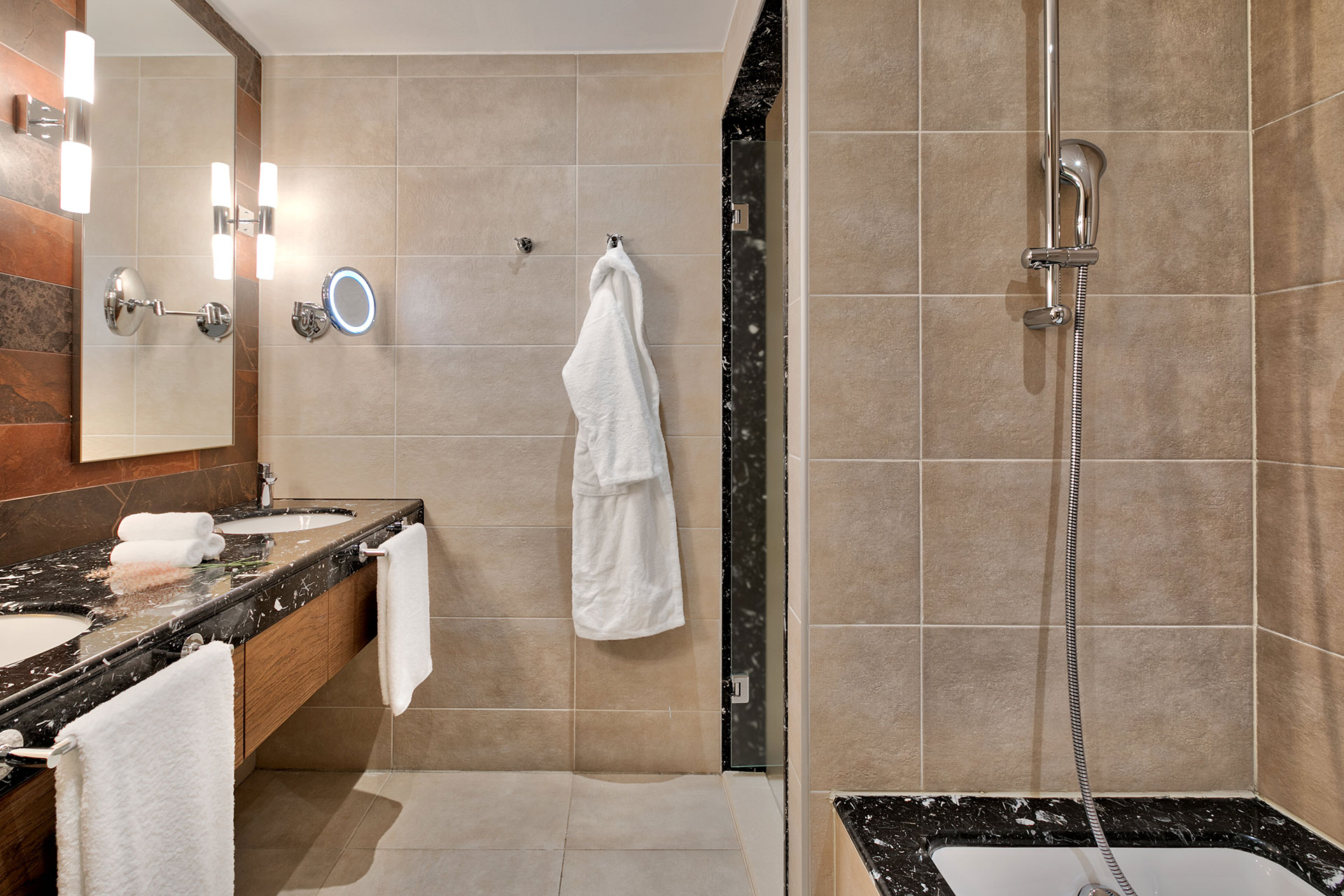 Family room's spacious bathroom with dual basins, marble counter top and bathtub, and vanity mirror