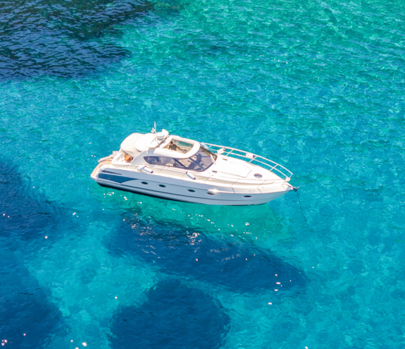 Motor yacht floating on crystal-clear turquoise water under bright summer light