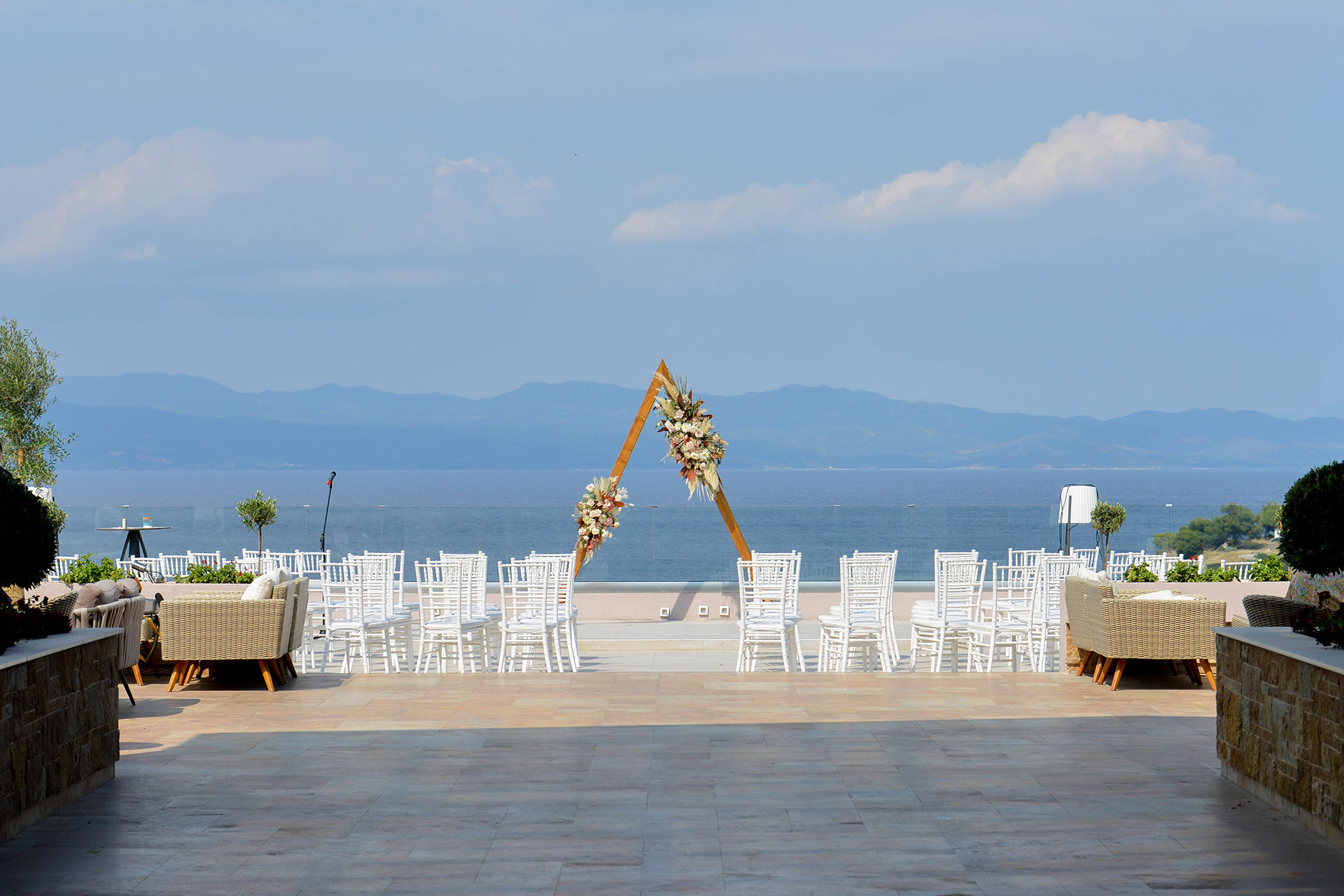 Stylish seaside wedding ceremony setup with floral arch and elegant white chairs
