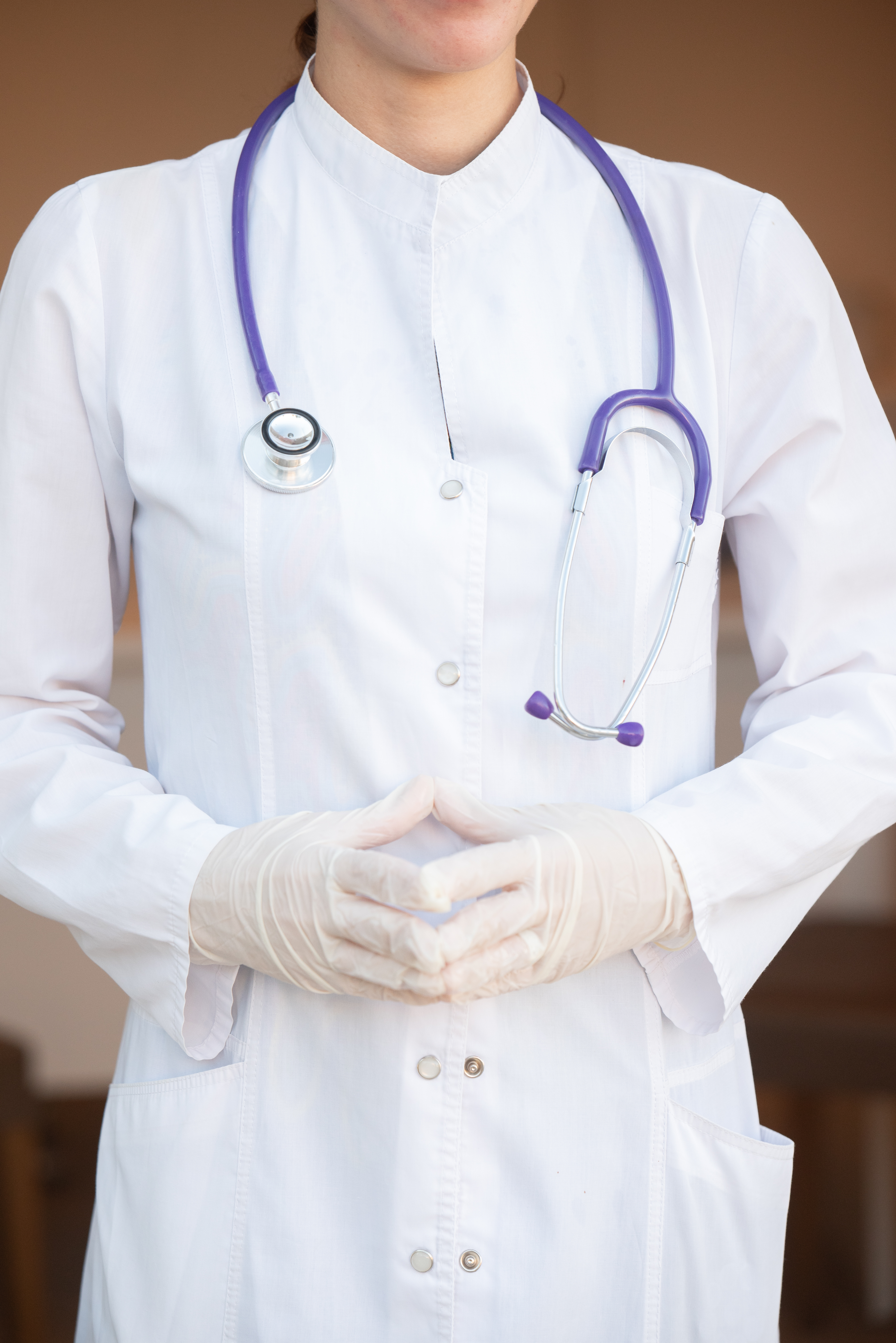 Medical professional wearing white coat, gloves, and a stethoscope